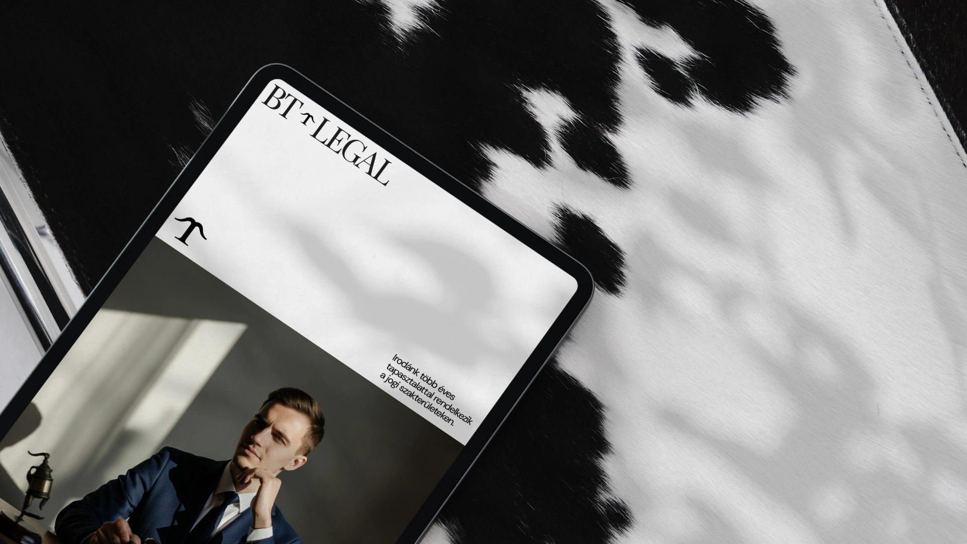 BT Legal arculattervezés: tablet mockup a klasszikus talpas BT Legal logóval, monogrammal és öltönyös férfi fotójával elegáns fekete-fehér környezetben