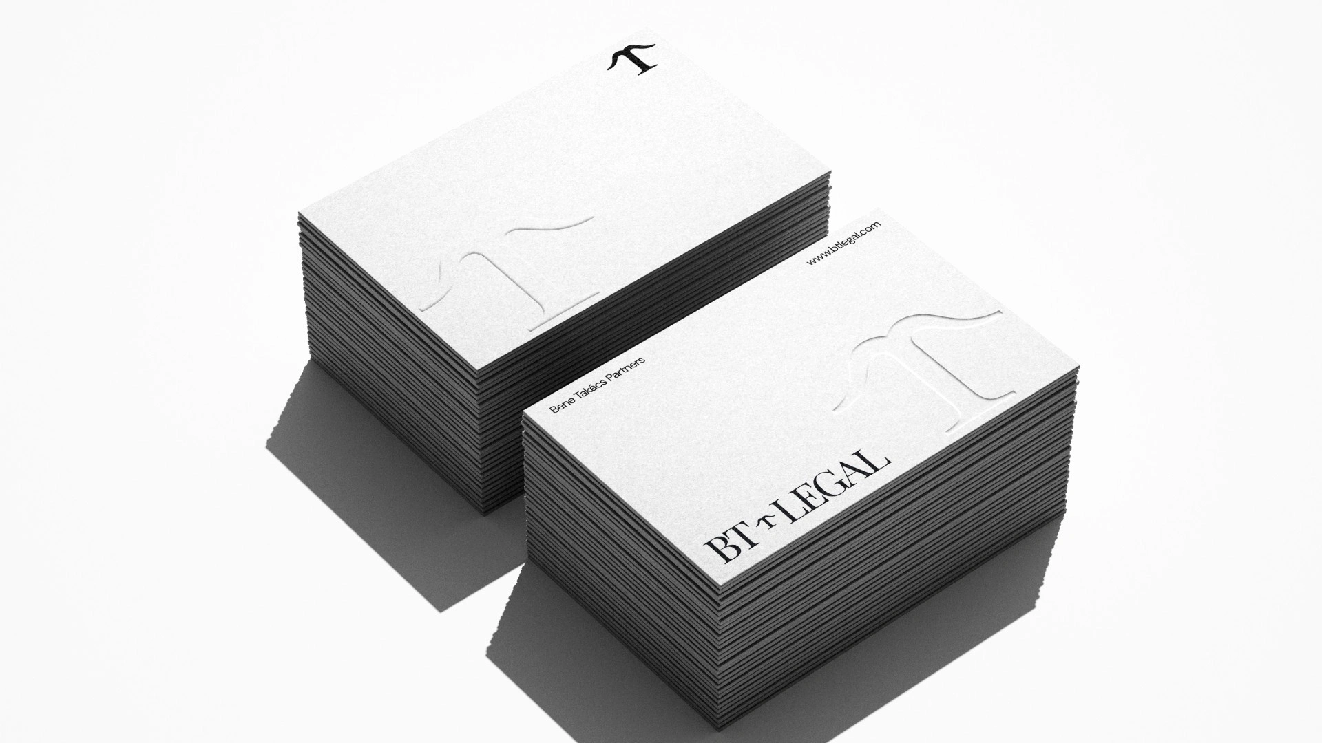 BT Legal arculattervezés: fehér névjegykártya mockup domborított monogrammal, talpas BT Legal logóval és Bene Takács Partners felirattal
