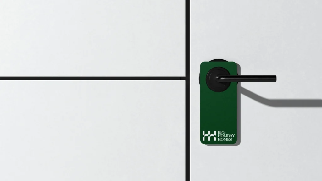 BFG Holiday Homes arculattervezés: sötétzöld kilincsakasztó mockup fehér H-monogram logóval minimalista ajtó kilincsén